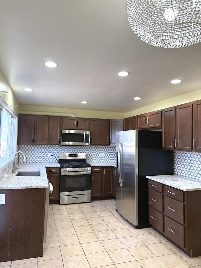 kitchen with light stone countertops, sink, appliances with stainless steel finishes, and tasteful backsplash