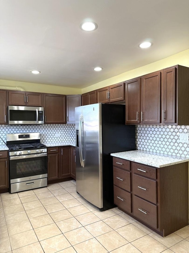 kitchen featuring decorative backsplash, appliances with stainless steel finishes, light stone counters, and dark brown cabinets