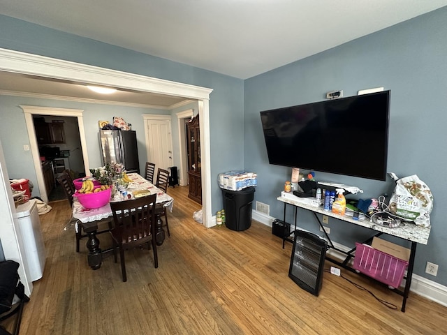 dining space with light hardwood / wood-style flooring and crown molding