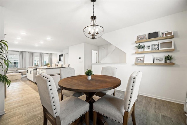 dining area with sink, light hardwood / wood-style flooring, and an inviting chandelier