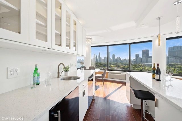 kitchen with white cabinetry, sink, dishwasher, light stone countertops, and decorative light fixtures