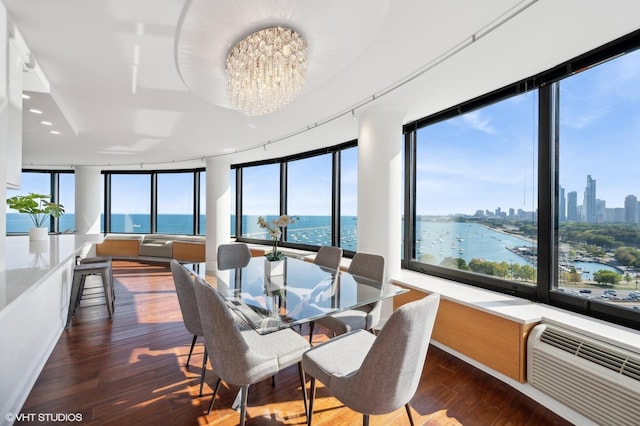 sunroom with a chandelier, a water view, a wall unit AC, and a healthy amount of sunlight