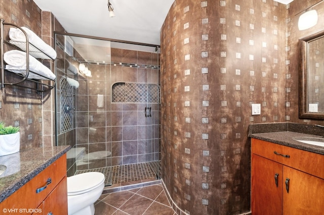 bathroom with tile patterned floors, vanity, toilet, and tiled shower