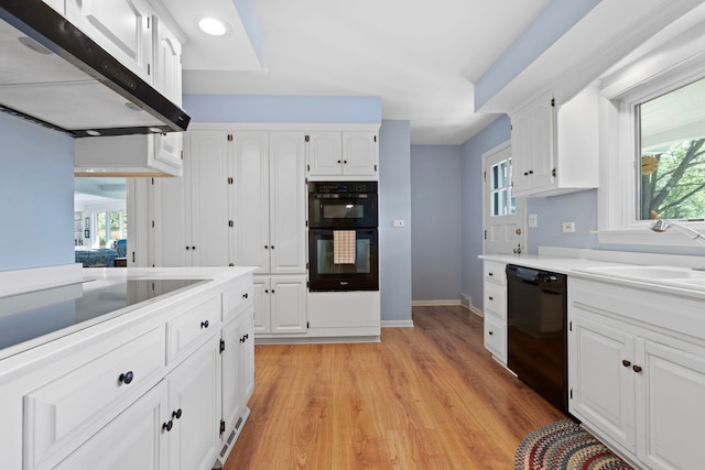 kitchen with black appliances, light hardwood / wood-style floors, white cabinetry, and sink