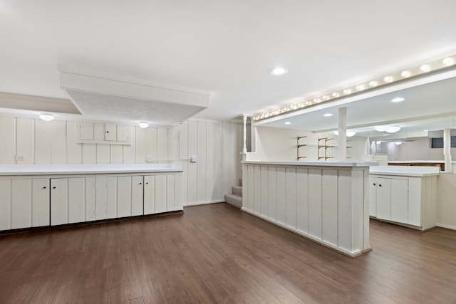 kitchen featuring kitchen peninsula, white cabinets, and dark wood-type flooring