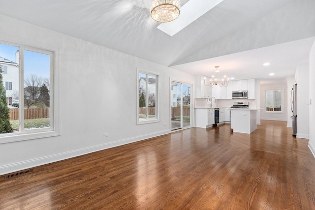 unfurnished living room featuring lofted ceiling, dark hardwood / wood-style floors, a notable chandelier, and sink