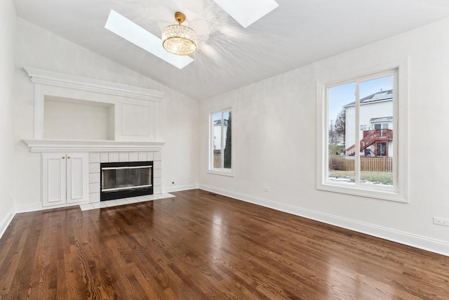 unfurnished living room featuring hardwood / wood-style floors, lofted ceiling with skylight, and a fireplace