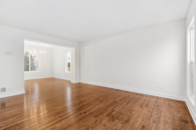 unfurnished room featuring wood-type flooring and a chandelier