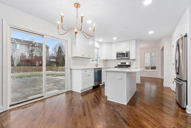 kitchen with a center island, hanging light fixtures, dark hardwood / wood-style floors, white cabinetry, and stainless steel appliances