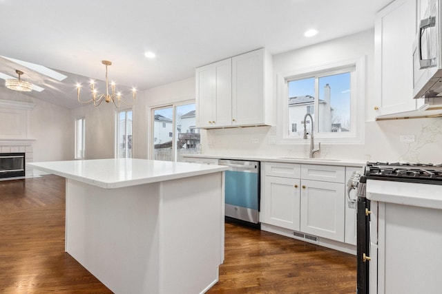 kitchen featuring a center island, sink, decorative light fixtures, white cabinets, and appliances with stainless steel finishes