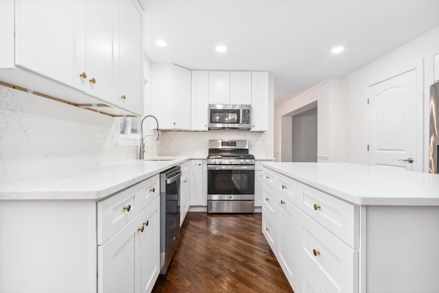 kitchen with sink, dark wood-type flooring, stainless steel appliances, a kitchen island, and white cabinets