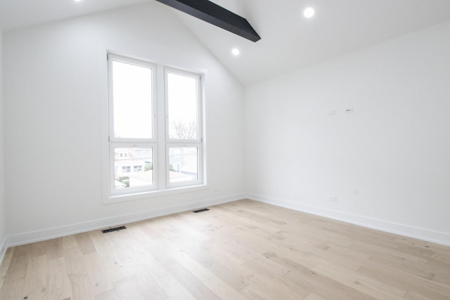 spare room featuring vaulted ceiling with beams and light hardwood / wood-style floors