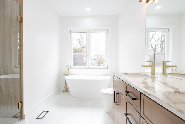 bathroom featuring vanity, a healthy amount of sunlight, toilet, and a tub