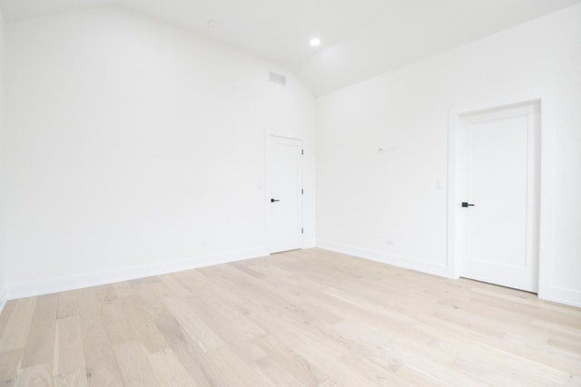 spare room with lofted ceiling and light wood-type flooring