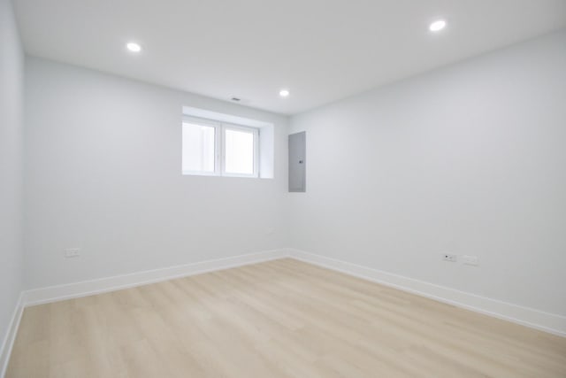 spare room featuring electric panel and light hardwood / wood-style flooring