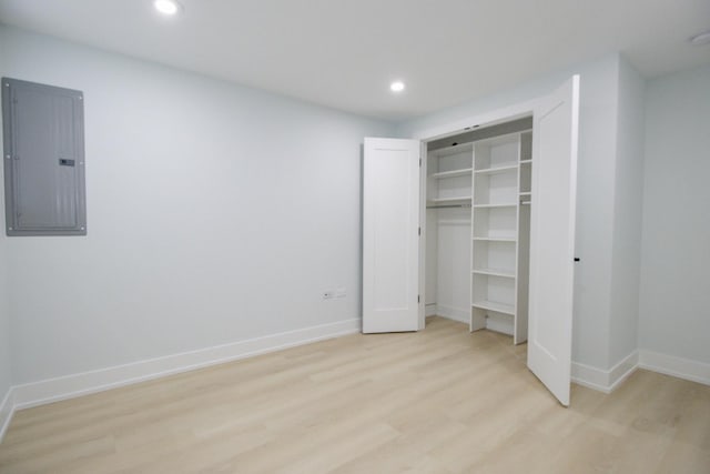 unfurnished bedroom featuring light wood-type flooring, electric panel, and a closet