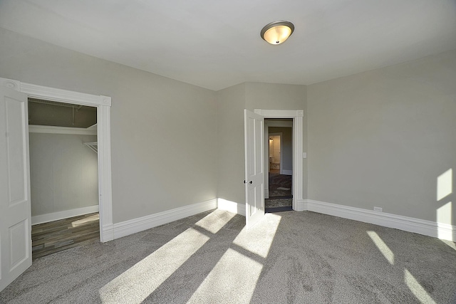 unfurnished bedroom with a closet and dark colored carpet