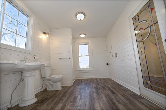 bathroom with hardwood / wood-style flooring, toilet, and wood walls