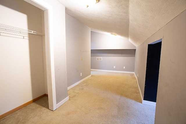 additional living space featuring light carpet, lofted ceiling, and a textured ceiling