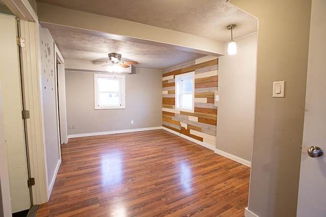 unfurnished room featuring ceiling fan, wooden walls, dark hardwood / wood-style floors, and a textured ceiling