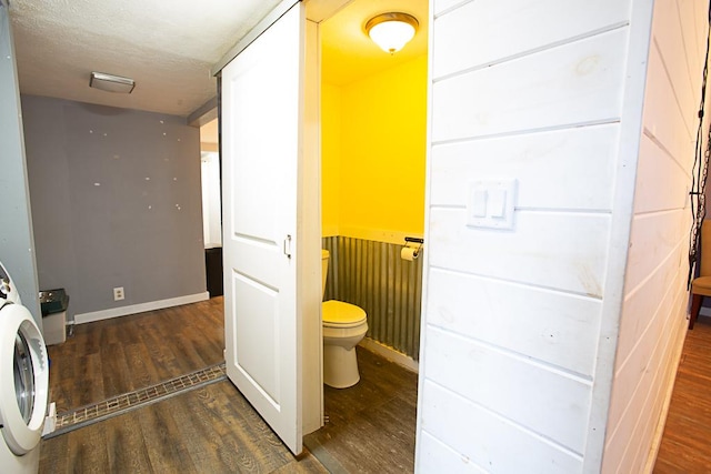 bathroom with hardwood / wood-style flooring, washer / dryer, and toilet