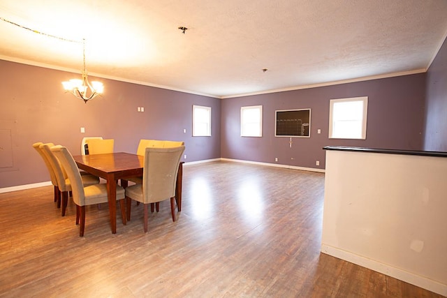 dining room with hardwood / wood-style floors, a textured ceiling, ornamental molding, and a chandelier