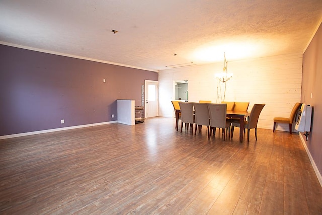 dining room featuring dark hardwood / wood-style floors, heating unit, ornamental molding, a notable chandelier, and a textured ceiling