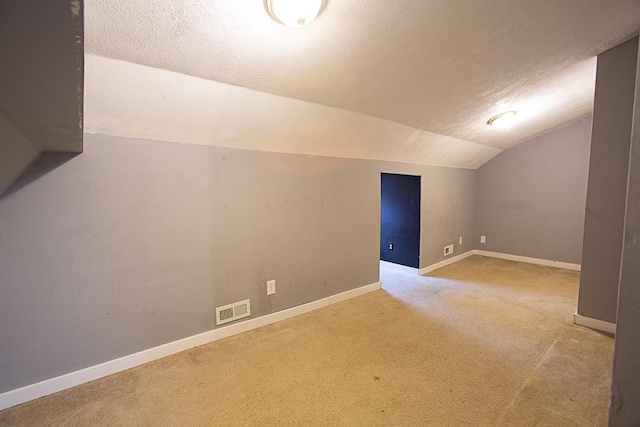 bonus room with lofted ceiling, light carpet, and a textured ceiling