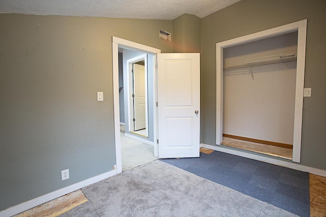 unfurnished bedroom with light carpet, vaulted ceiling, a closet, and a textured ceiling