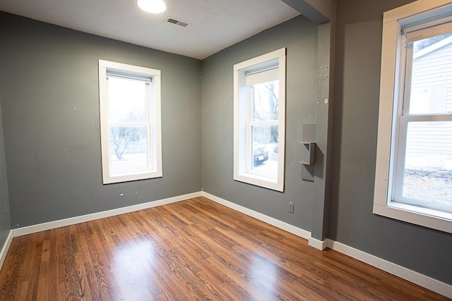 empty room with plenty of natural light and hardwood / wood-style floors