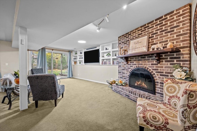 living room featuring rail lighting, built in features, a fireplace, and carpet floors