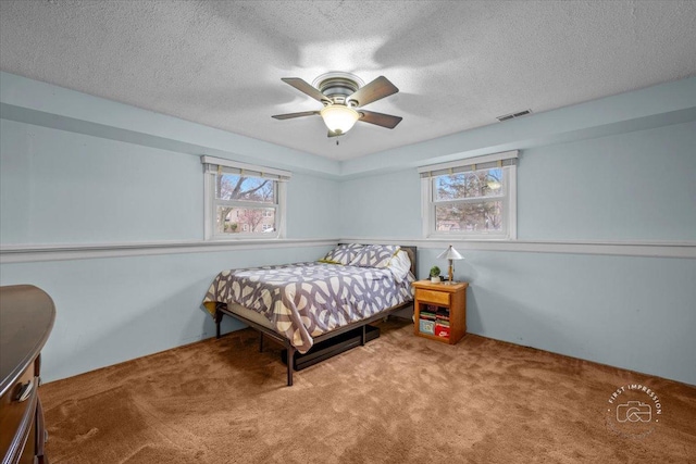 carpeted bedroom featuring ceiling fan, a textured ceiling, and multiple windows