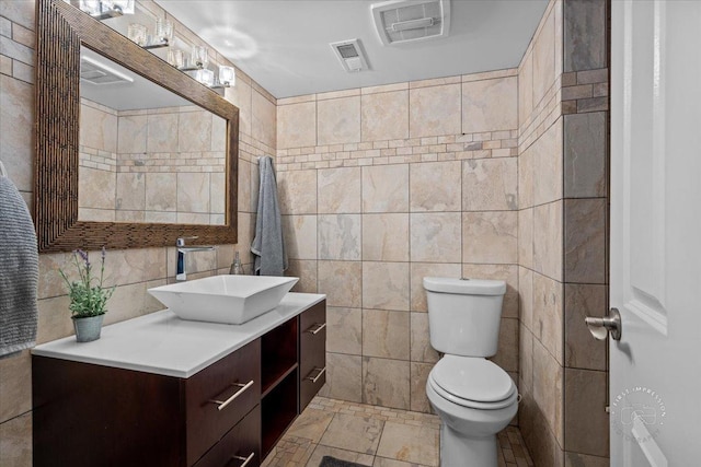 bathroom featuring vanity, toilet, and tile walls