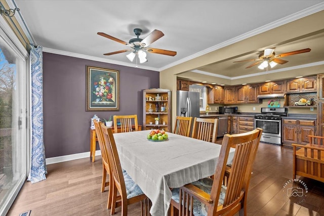 dining area featuring ceiling fan, light wood-type flooring, and ornamental molding