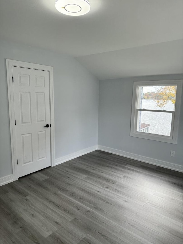 unfurnished room featuring dark hardwood / wood-style flooring and lofted ceiling