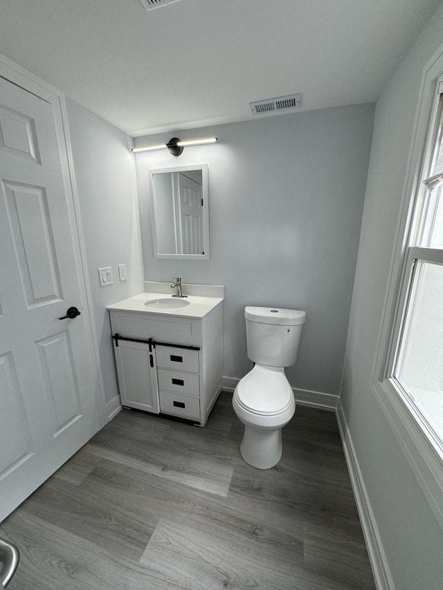 bathroom with hardwood / wood-style flooring, vanity, and toilet