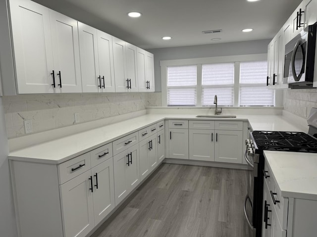 kitchen featuring sink, white cabinetry, stainless steel appliances, and light hardwood / wood-style flooring