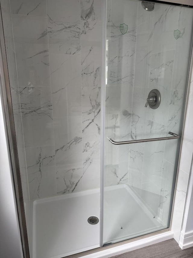 bathroom featuring wood-type flooring and an enclosed shower