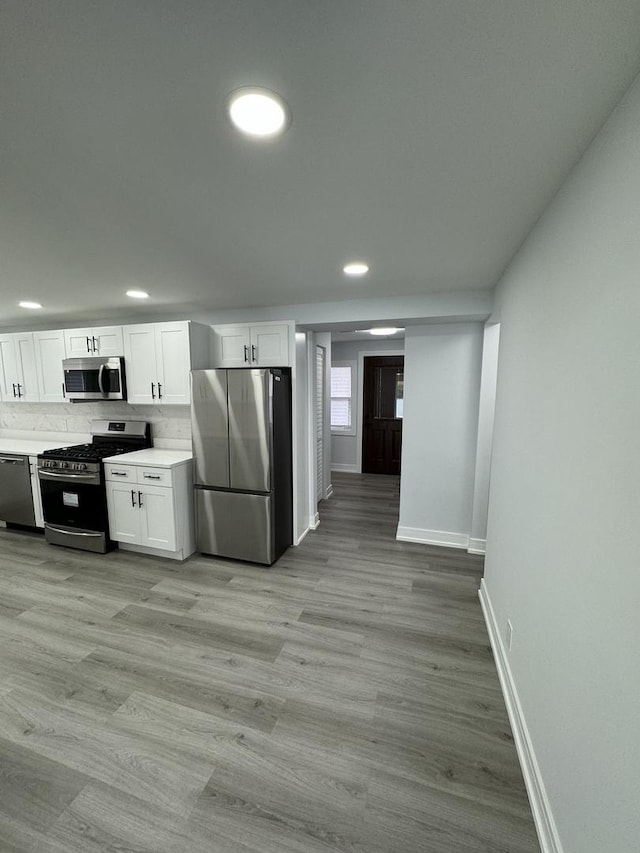 kitchen featuring decorative backsplash, stainless steel appliances, white cabinetry, and light hardwood / wood-style flooring