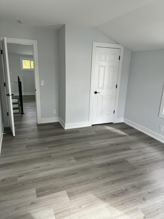 spare room with hardwood / wood-style floors and vaulted ceiling