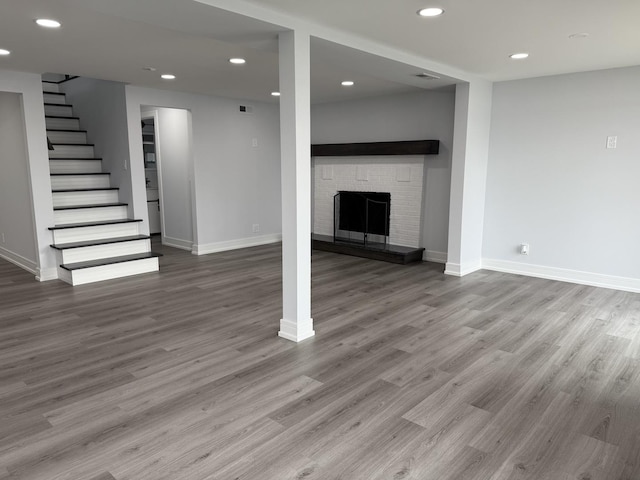 basement featuring hardwood / wood-style floors and a stone fireplace