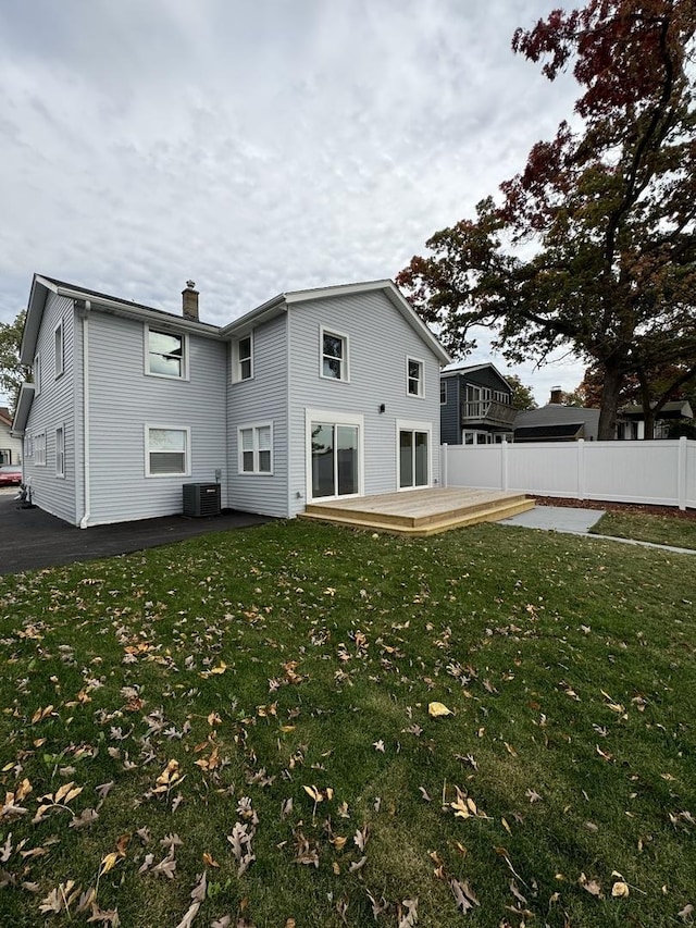 back of property with a yard, a wooden deck, and central air condition unit