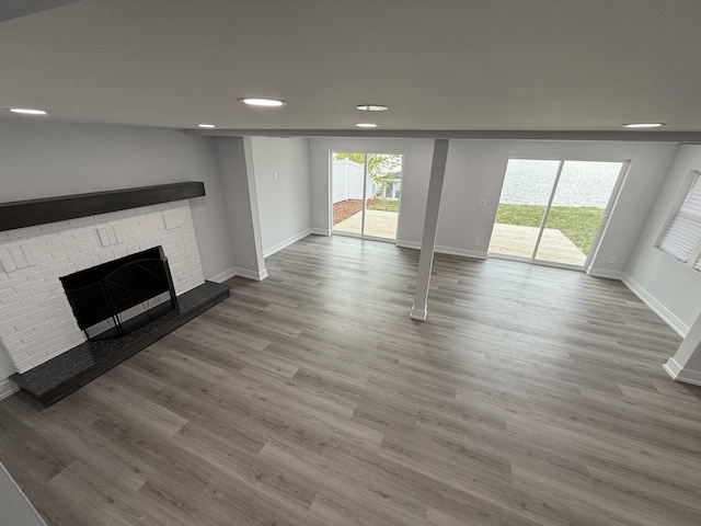 unfurnished living room with hardwood / wood-style floors and a brick fireplace