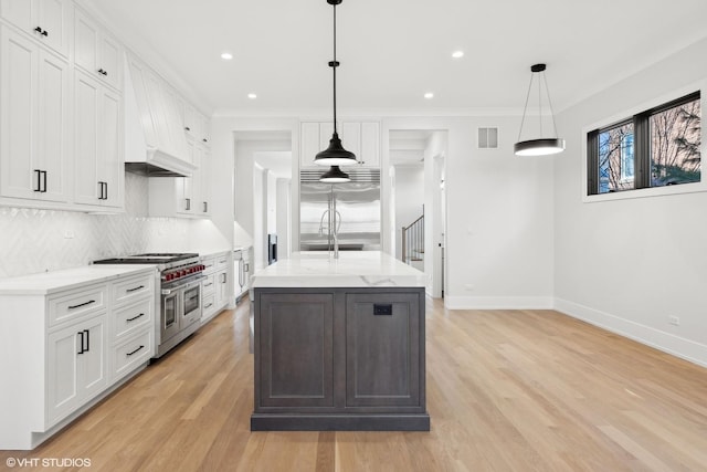 kitchen featuring high end appliances, white cabinets, and decorative light fixtures