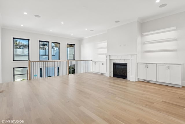 unfurnished living room with ornamental molding, a high end fireplace, and light hardwood / wood-style floors