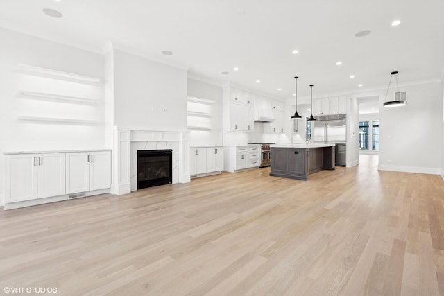 unfurnished living room with a premium fireplace, crown molding, and light wood-type flooring