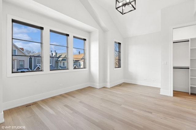 unfurnished bedroom with an inviting chandelier, light hardwood / wood-style flooring, and vaulted ceiling