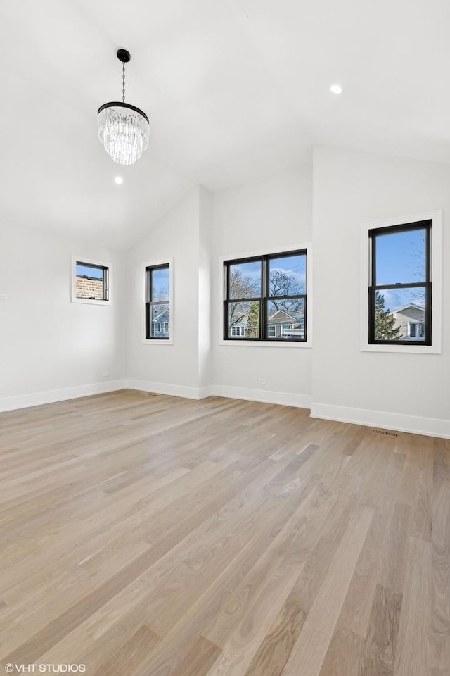 unfurnished room with lofted ceiling, a notable chandelier, and light hardwood / wood-style floors