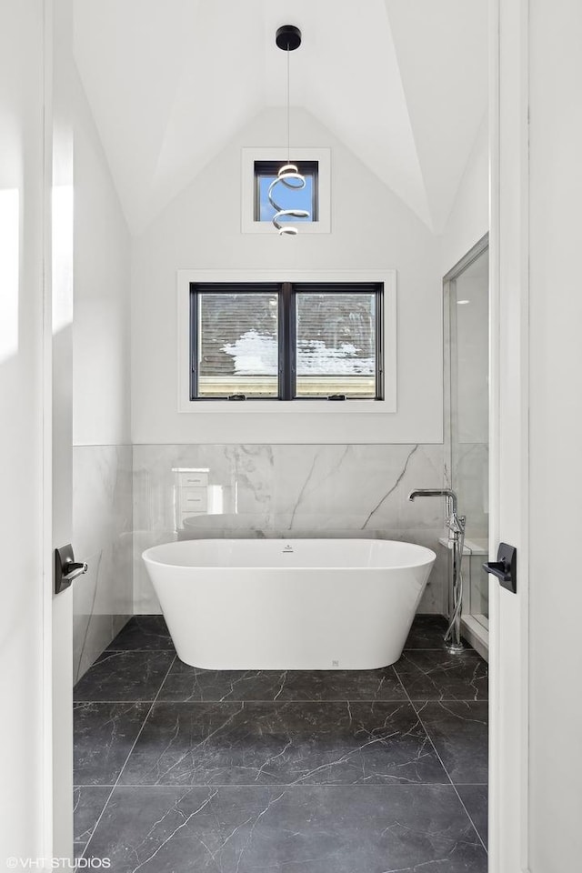 bathroom featuring a tub to relax in and vaulted ceiling