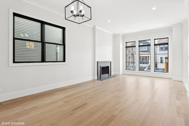 unfurnished living room featuring a premium fireplace, light wood-type flooring, a chandelier, and crown molding